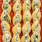 a close up shot of vegan ricotta spinach stuffed shells with homemade marinara before baking by sweet simple vegan