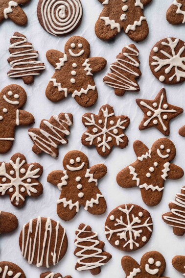 An overhead shot of iced vegan gingerbread cookies on a white marble board