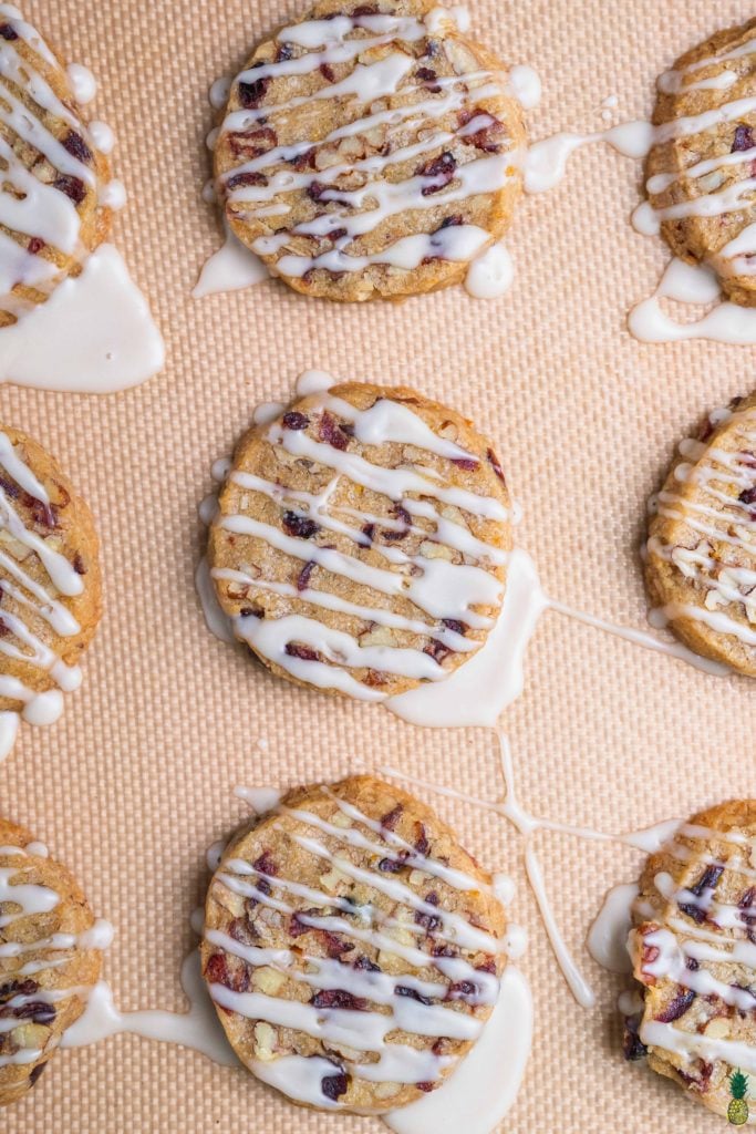 Overhead shot of pecan cranberry orange shortbread cookies on a baking sheet with icing