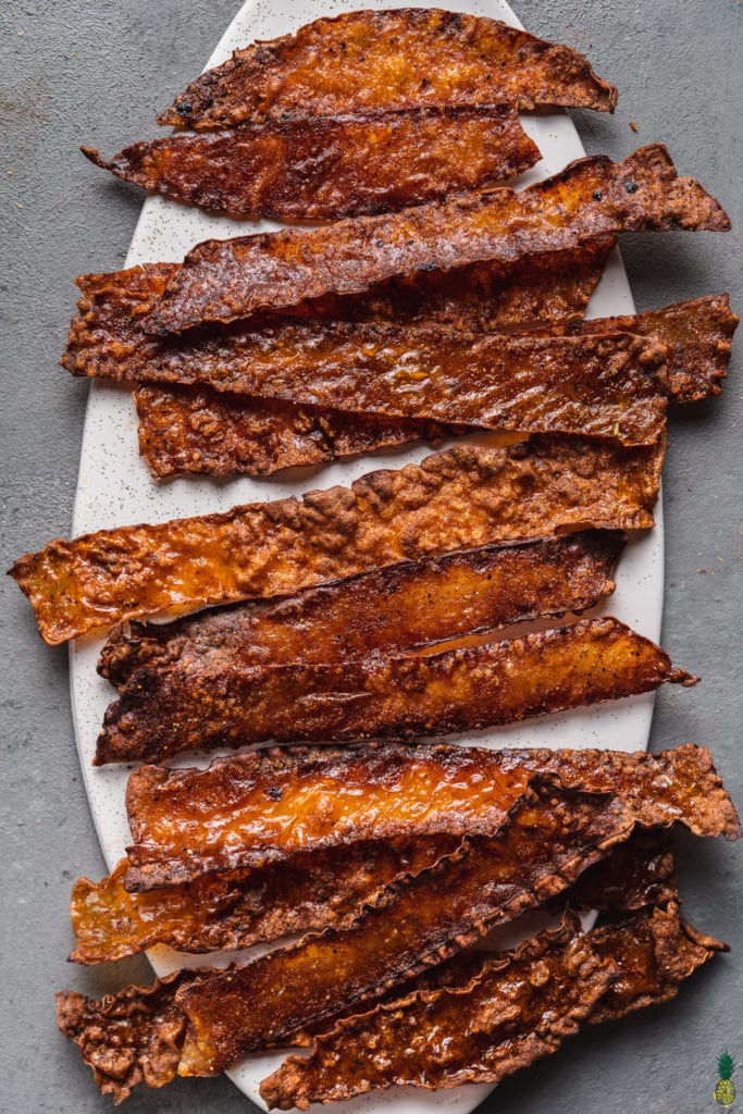 baked crispy vegan rice paper bacon on a white serving plate by sweet simple vegan