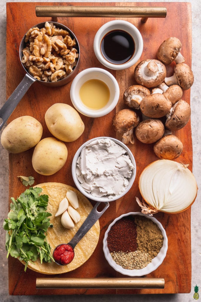 A photo of ingredients needed to make mushroom potato taquitos on a wooden board