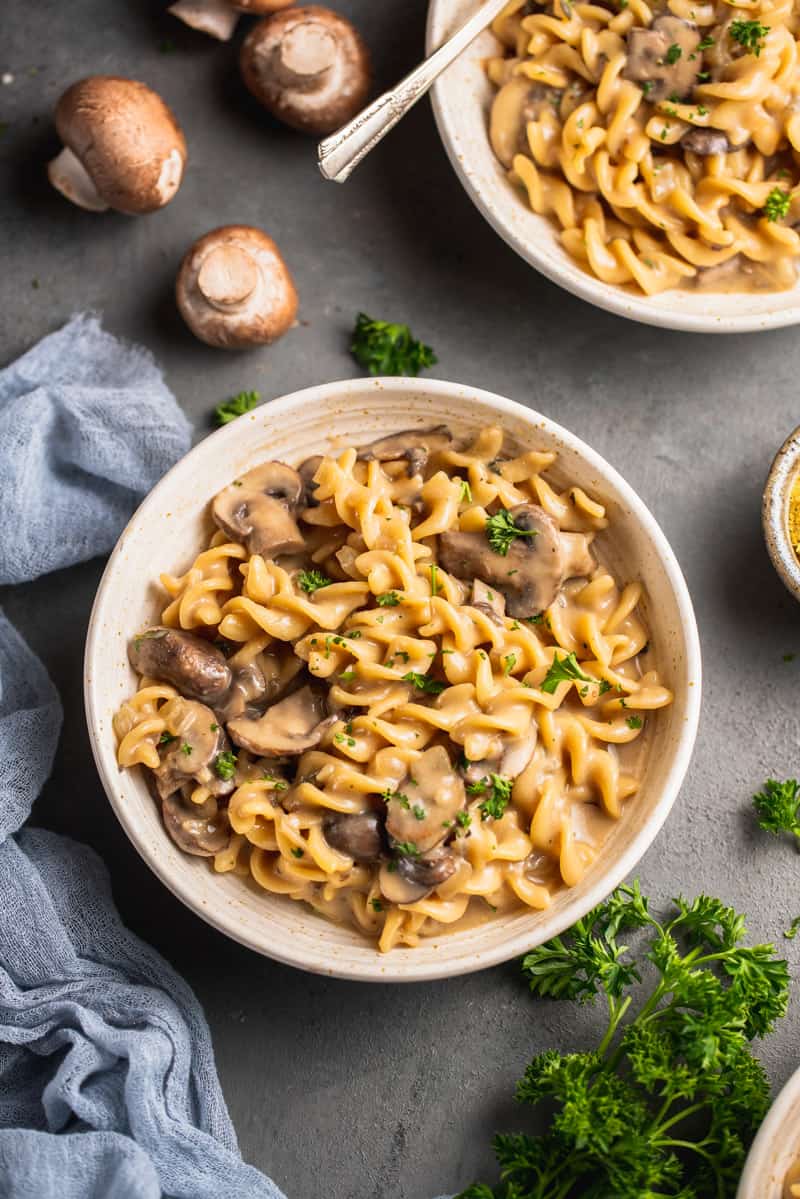 white bowl of mushroom stroganoff styled on grey background with blue towel