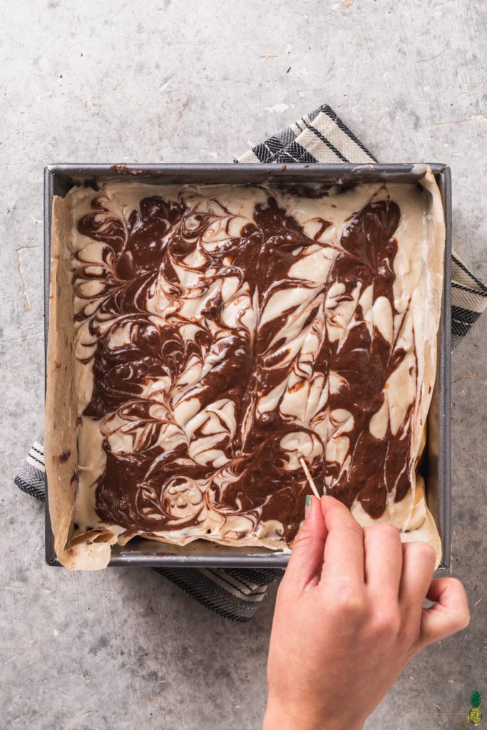 A step by step shot of a swirled vegan cheesecake brownie by sweet simple vegan