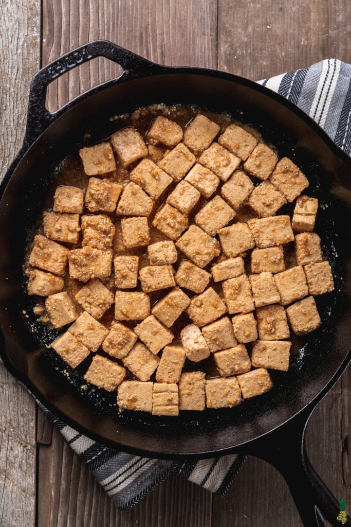 Over head image of uncooked sesame ginger tofu in cast iron skillet. 