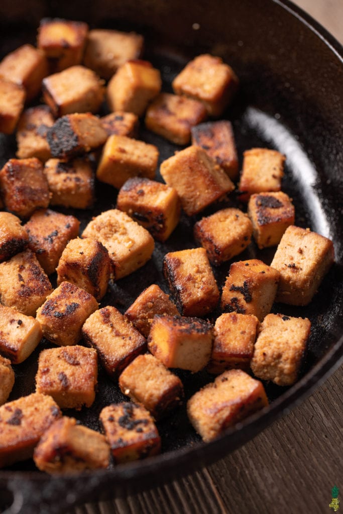 sesame ginger tofu in a cast iron skillet close up shot taken at 3/4 angle.