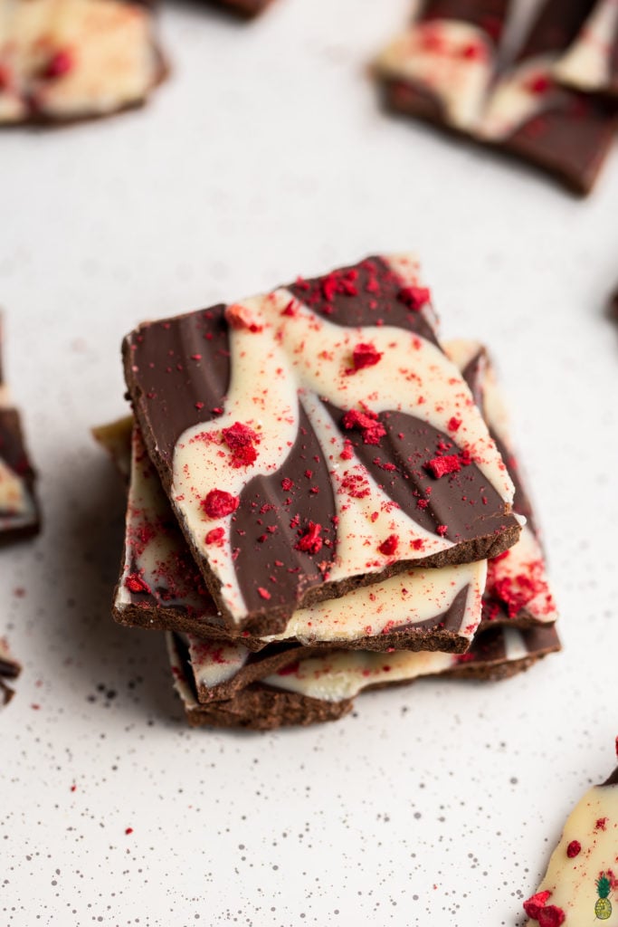 a photo of a pile of swirled chocolate bark with raspberries by sweet simple vegan