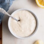 A bowl of homemade garlic aioli with a spoon by sweet simple vegan