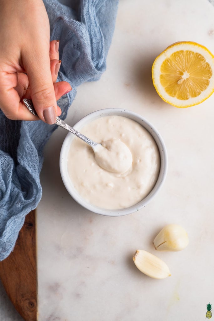 Scooping into a bowl of homemade garlic aioli by sweet simple vegan