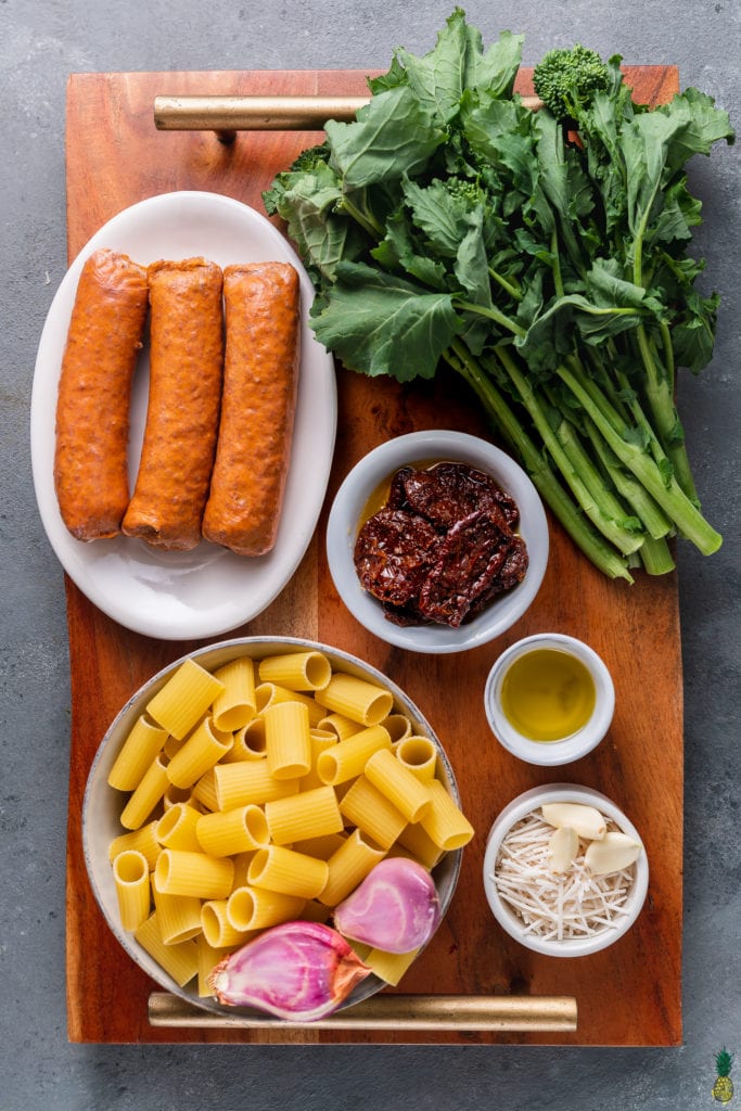 overhead photo of ingredients for Vegan Broccoli Rabe & Sausage Pasta on wooden board
