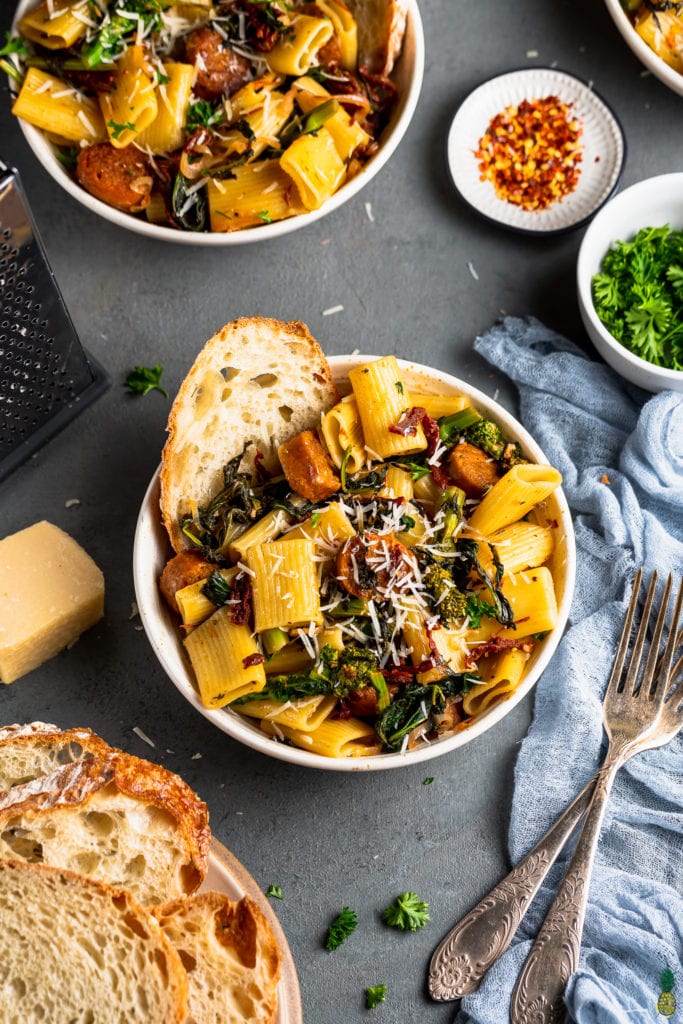 overhead styled photo of Vegan Broccoli Rabe & Sausage Pasta on grey background.