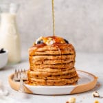 a stack of vegan carrot cake pancakes with a maple syrup drizzle