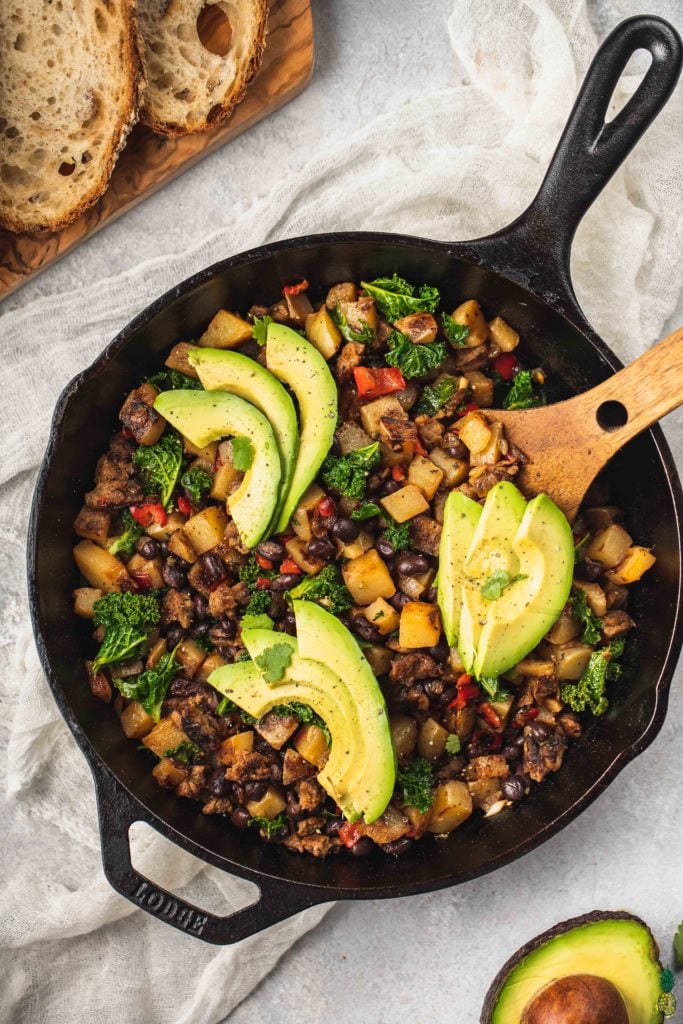 Vegan Breakfast Potato Hash with slices of avocado in a cast iron skillet by sweet simple vegan