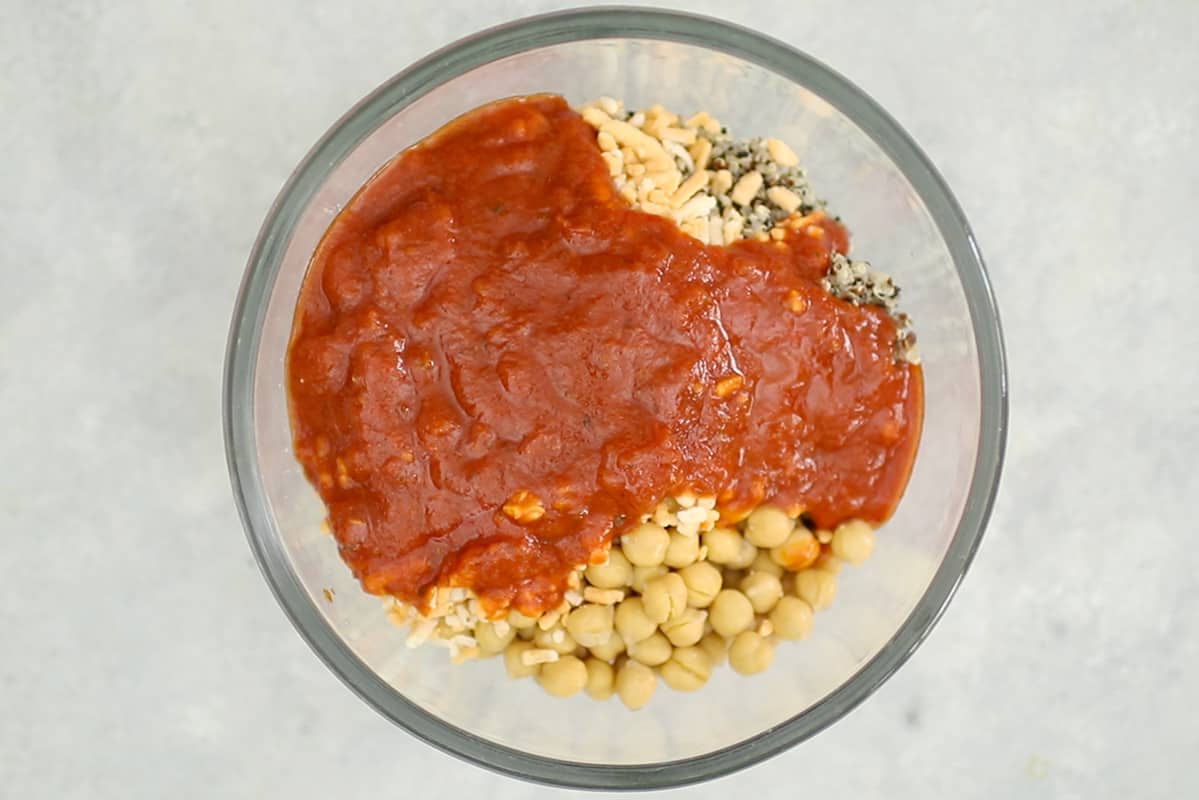 chickpeas, tomato sauce, vegan cheese and cooked rainbow quinoa in glass bowl