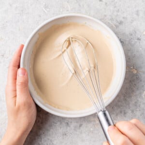 overhead image of bowl of tahini dressing with whisk