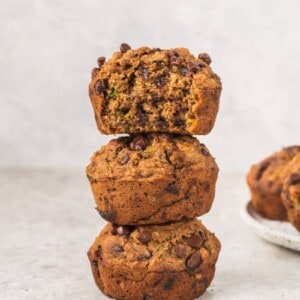 stacked chocolate chip zucchini muffins with a bite taken out of top one