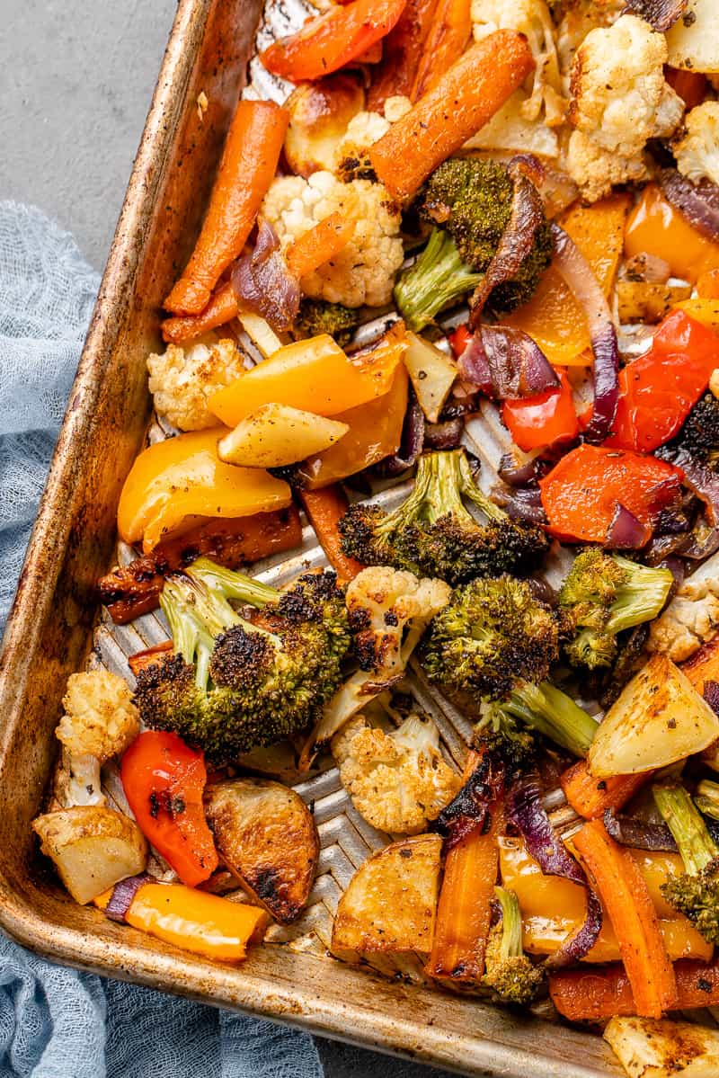 a close up of roasted vegetables on a silver baking sheet with a blue towel