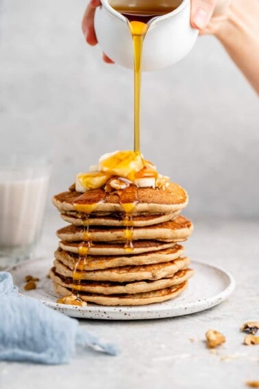 stack of blender oatmeal pancakes with maple syrup being poured over