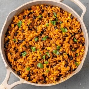 creamy vegan taco pasta in a beige pan with cilantro on top by sweet simple vegan
