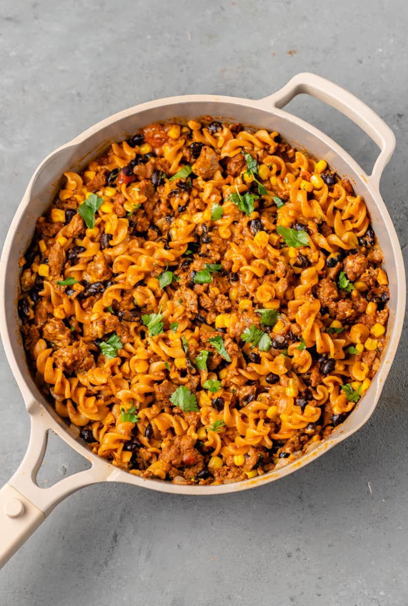 creamy vegan taco pasta in a beige pan with cilantro on top by sweet simple vegan