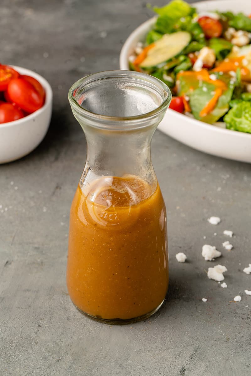 close up image of dressing in glass container with styled background.