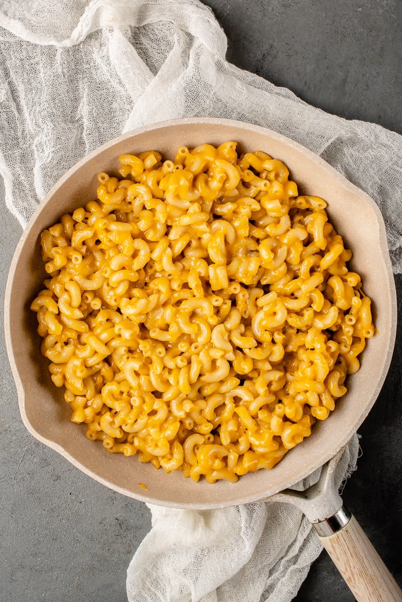 a shot of vegan mac and cheese in a white pot with a wooden handle