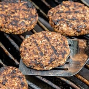 a spatula with a charred veggie burger on a grill