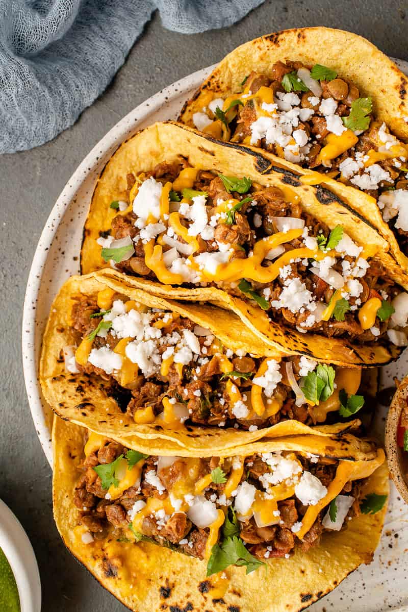 overhead image of lentil walnut tacos loaded with fixings on white speckled plate