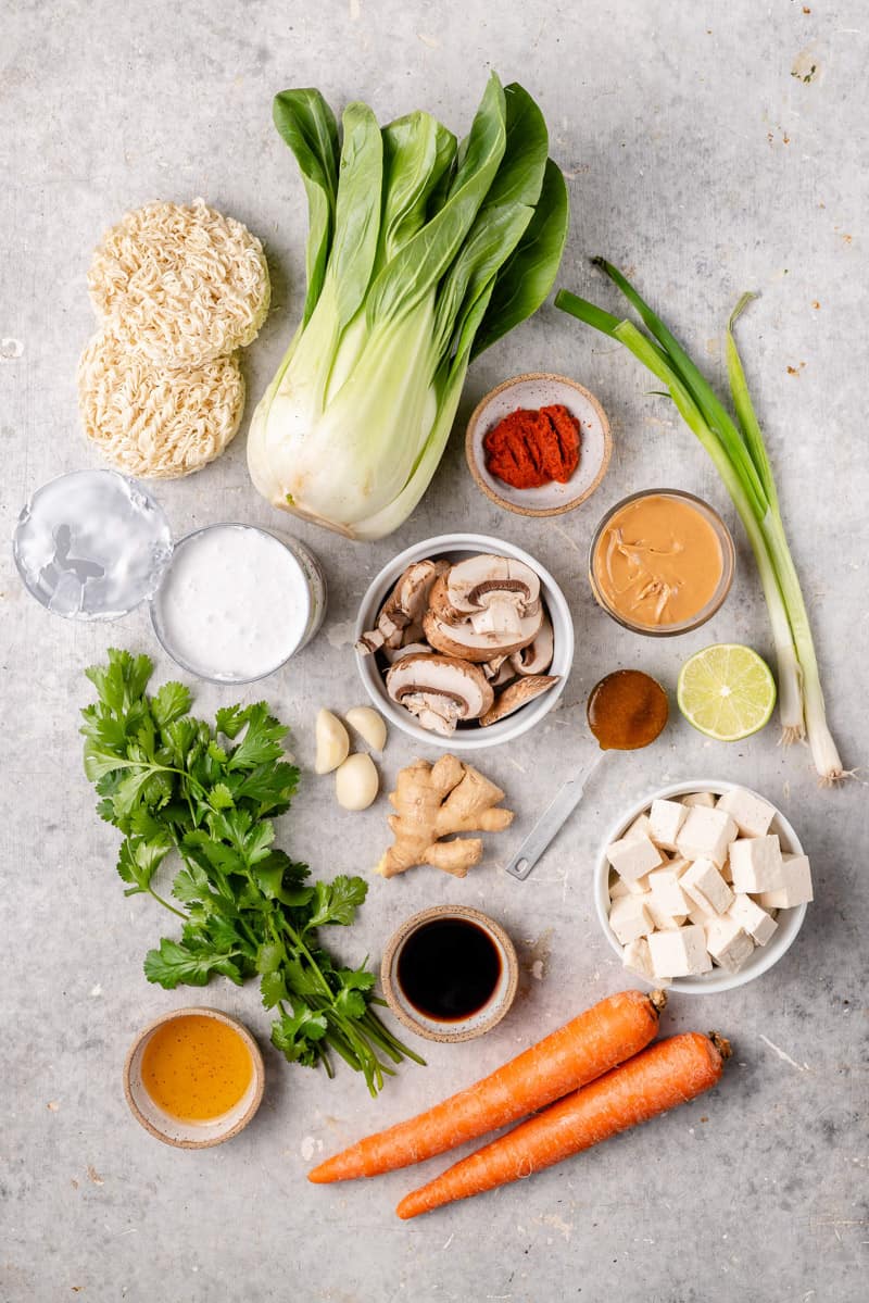 Ingredients needed to make a one pot red curry noodle soup on a gray board by sweetsimplevegan