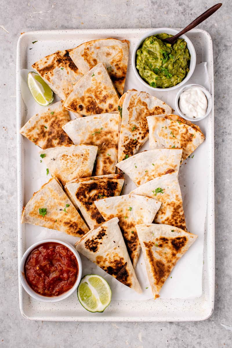 overhead image of potato & bean quesadillas in tray with salsa and guacamole