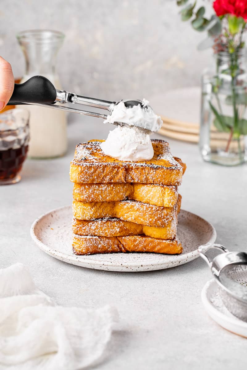 placing whipped cream on a stack of french toast