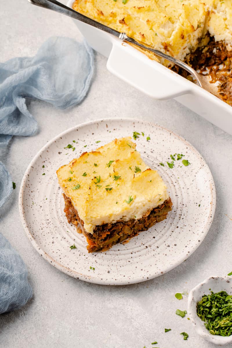 three quarter photo of vegan shepherd's pie on a plate with herbs