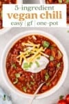 vegan chili in a white bowl with sour cream, cheese and cilantro for pinterest
