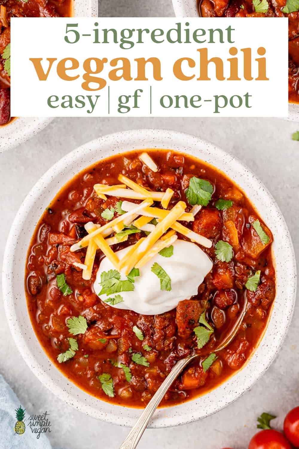 vegan chili in a white bowl with sour cream, cheese and cilantro for pinterest