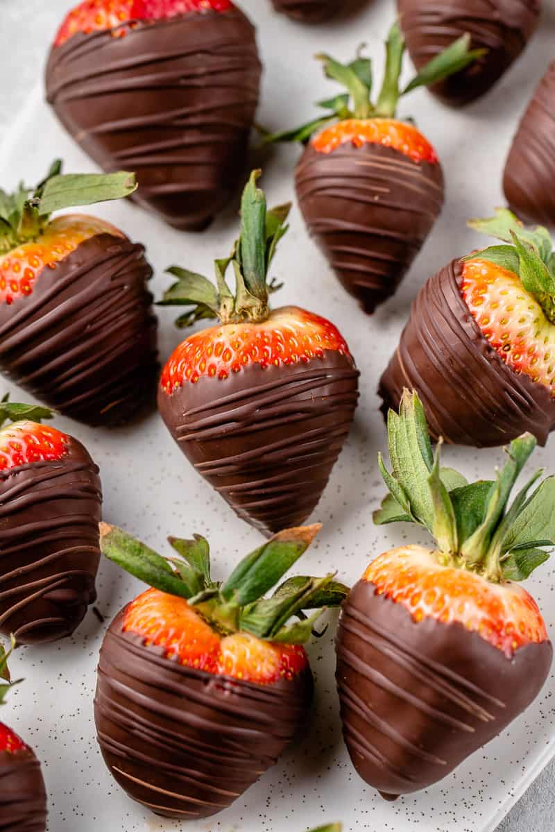 close up of a tray of chocolate covered strawberries with chocolate drizzle