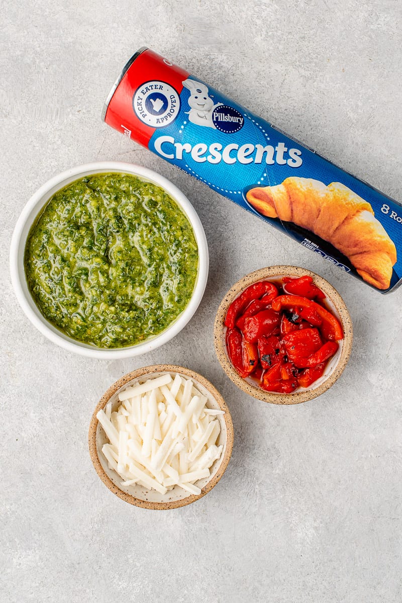 vegan pesto, roasted red peppers, vegan cheese and crescent rolls on a gray board