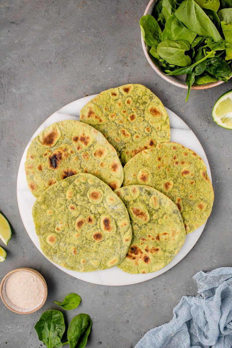 whole wheat spinach tortillas on a marble board surrounded by ingredients
