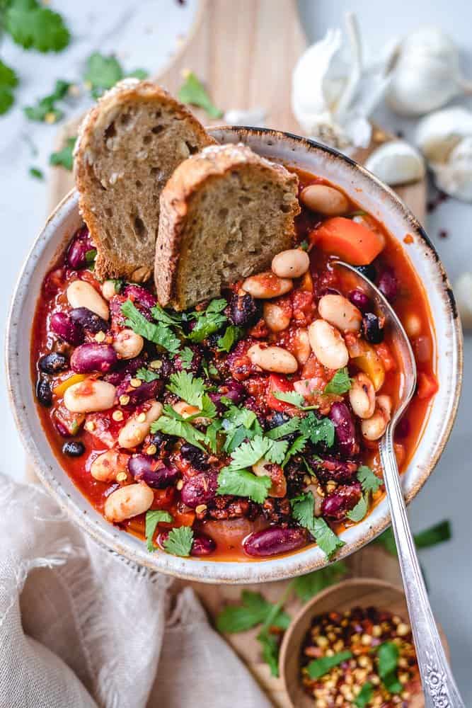 one-pot chili in a bowl with bread and spoon.