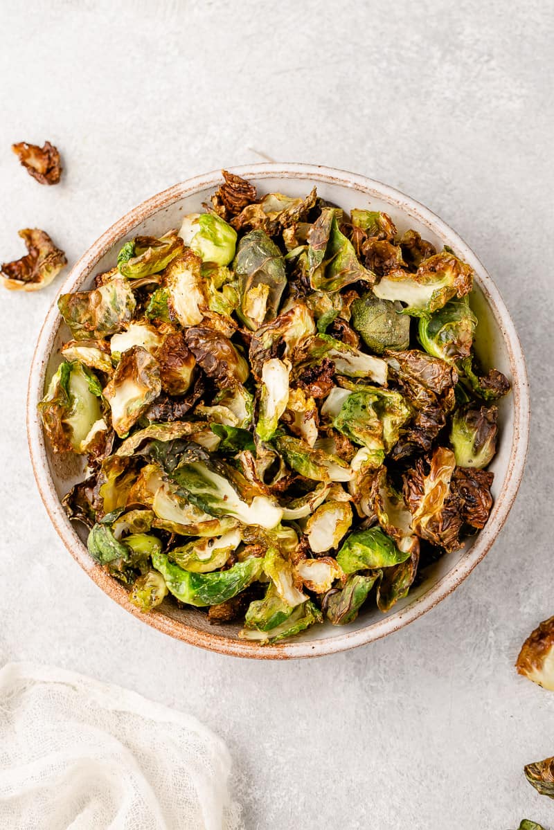 overhead image of cooked brussels sprout chips in a bowl