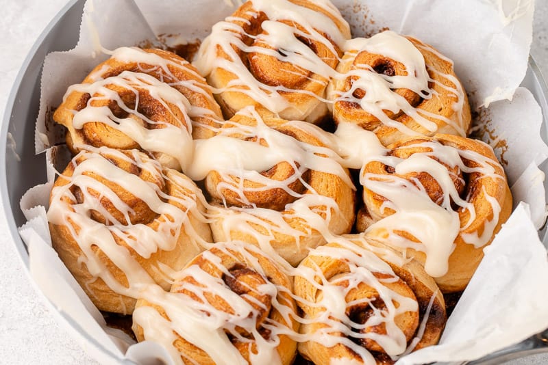 horizontal image of cooked cinnamon rolls drizzled with icing