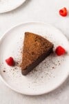 overhead image of chocolate soufflé cake dusted with cocoa powder up close with raspberries