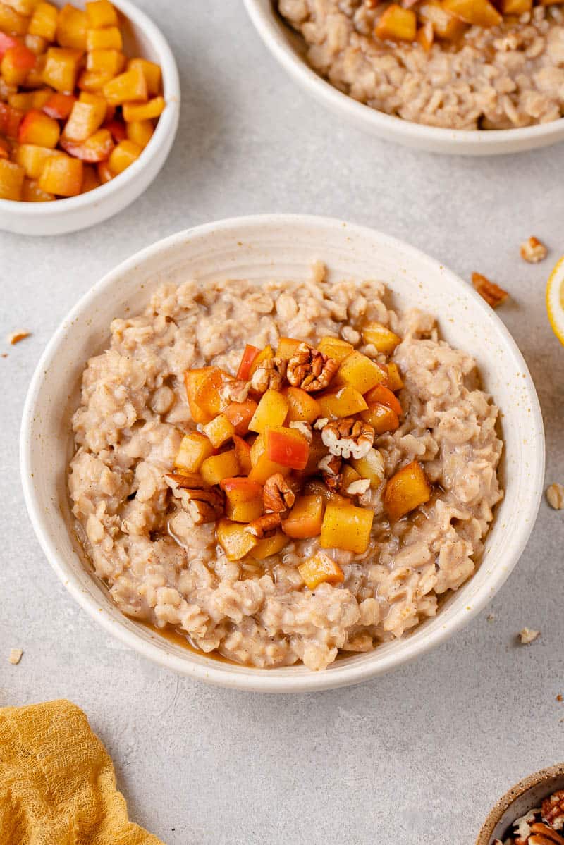 three quarter angle of apple cinnamon oatmeal in a bowl styled on a grey background