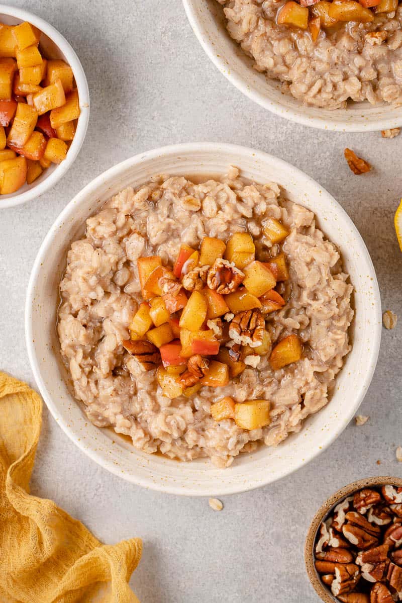 Overhead image of apple cinnamon oatmeal in bowl styled on a grey background