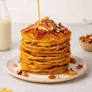 up close image of syrup being poured onto pumpkin pancakes