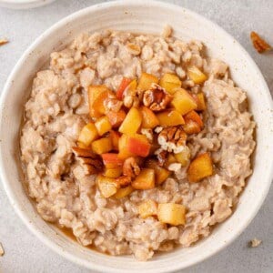 horizontal image of apple cinnamon oatmeal in bowl styled on a grey background