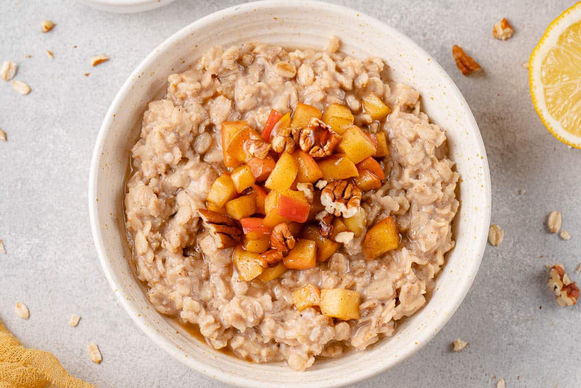 horizontal image of apple cinnamon oatmeal in bowl styled on a grey background