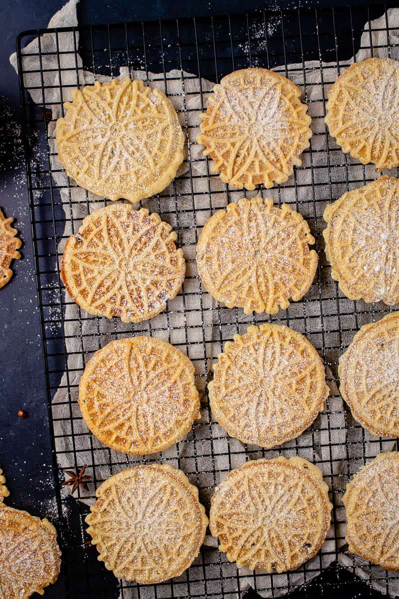 overhead image of pizzelles on cooling rack with parchment underneath