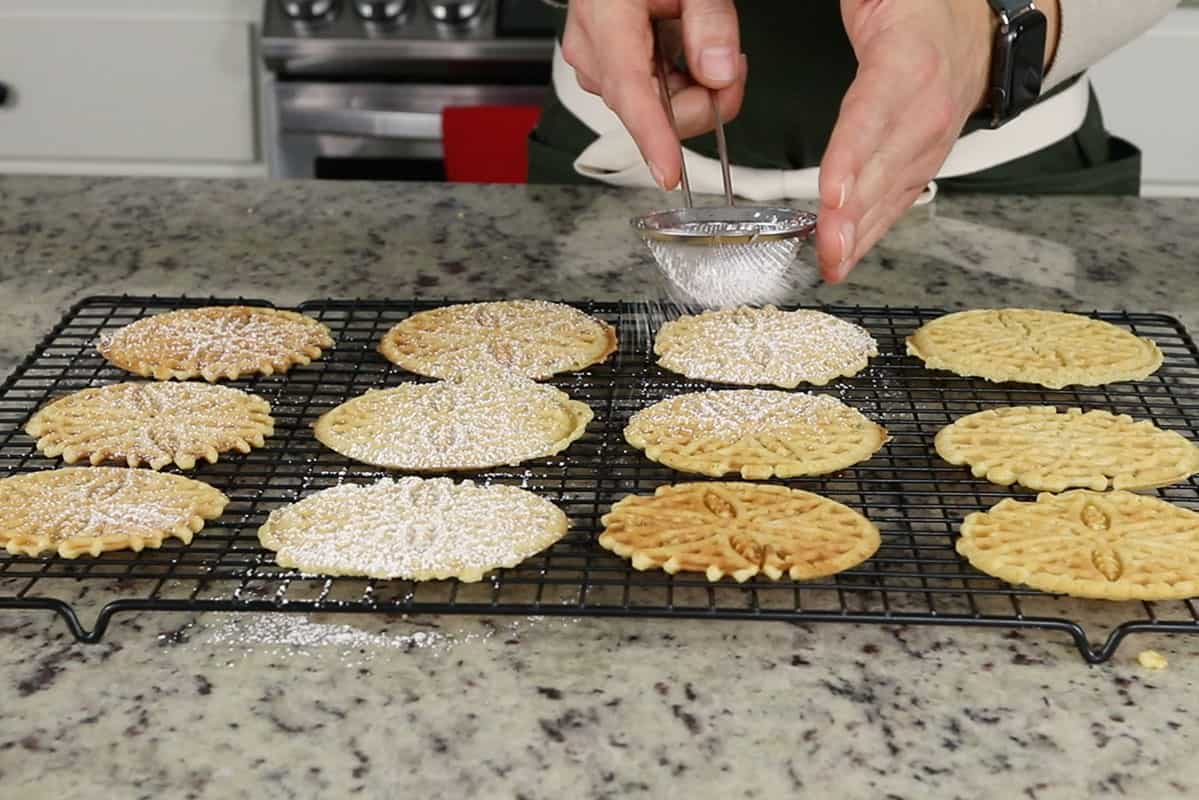 pizzelles being dusted with powdered sugar