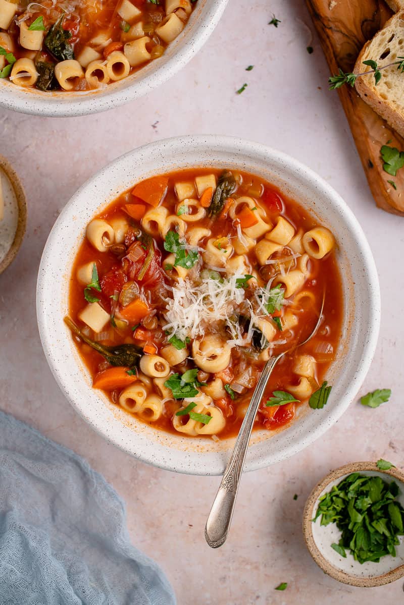 instant pot lentil soup in a white bowl with a spoon and parmesan