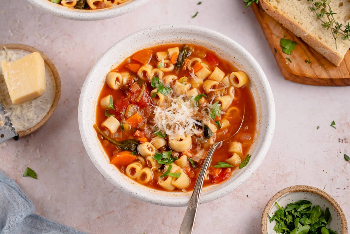 instant pot lentil soup in a white bowl with a spoon and parmesan