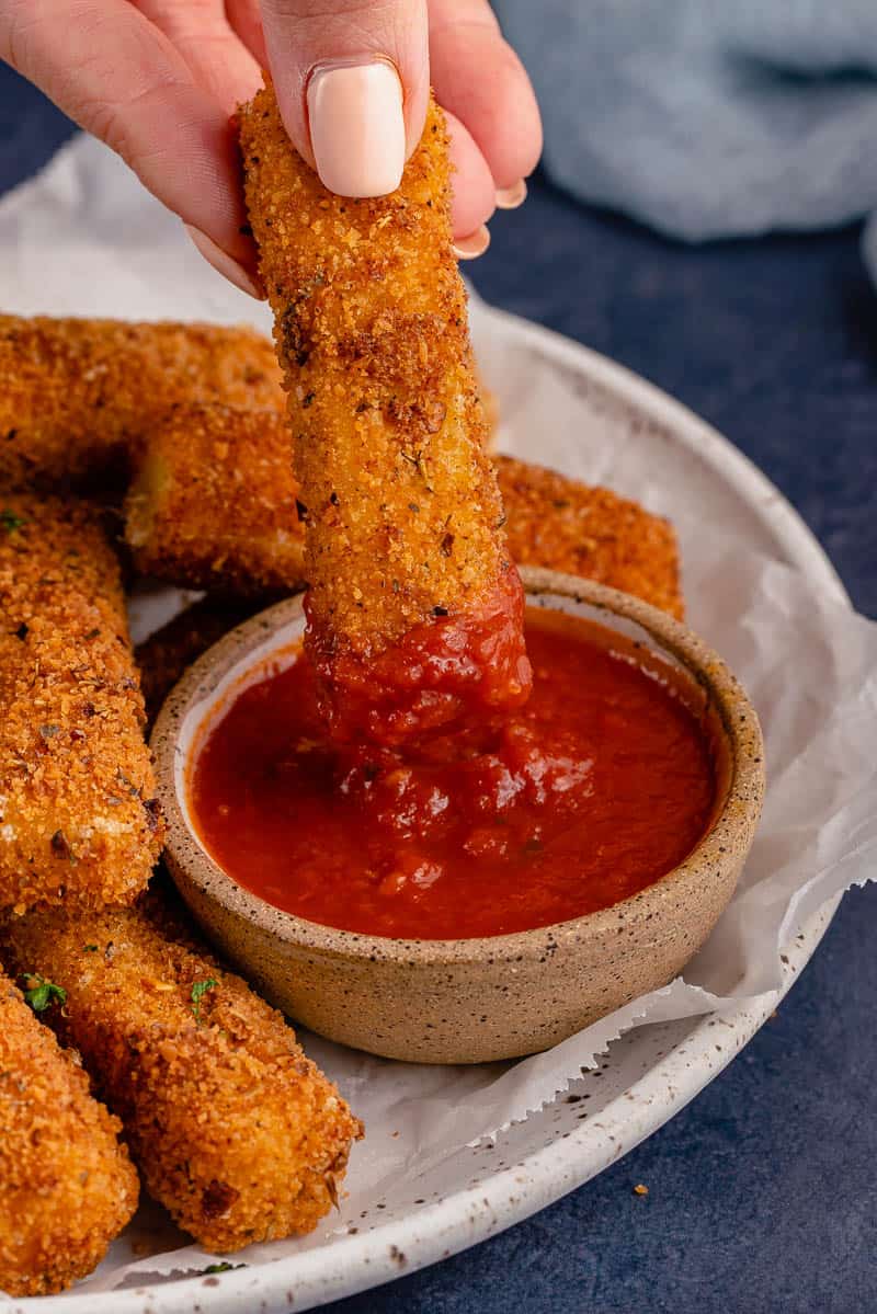 dipping Spicy Dairy-Free Mozzarella Sticks into marinara